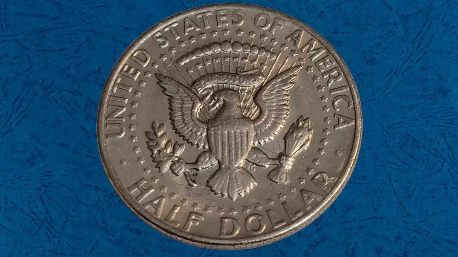 1973 Kennedy Half Dollar broadstrike error showing coin wider and flatter than normal with design spread outward, compared to standard size half dollar